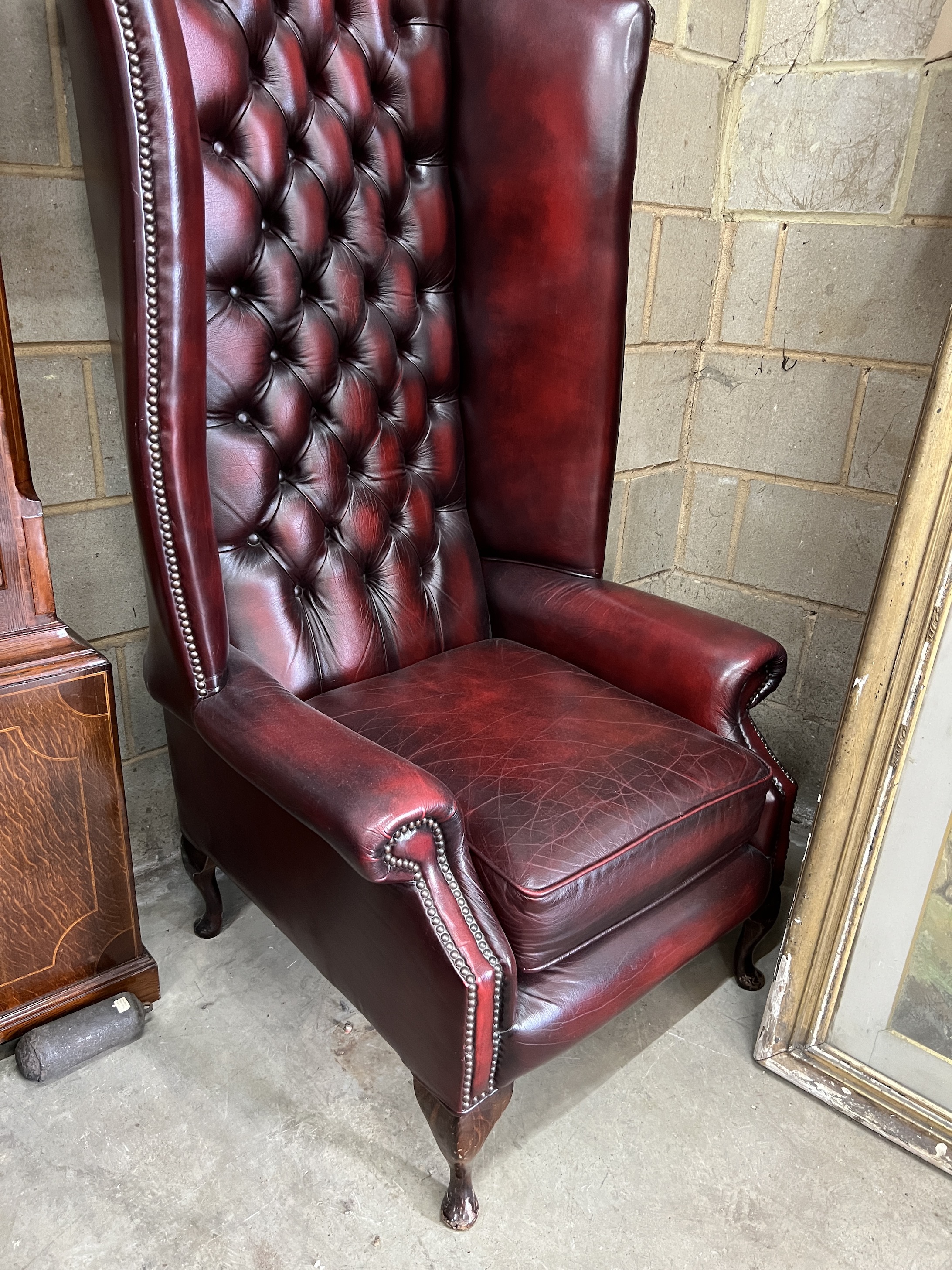 A pair of Victorian style buttoned burgundy leather high back wing armchairs, width 80cm, depth 86cm, height 152cm